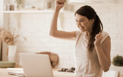 excited woman coach at her laptop with fist raised in the air