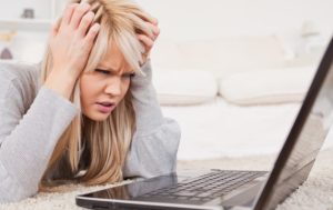 frustrated woman hands on forehead sitting at laptop